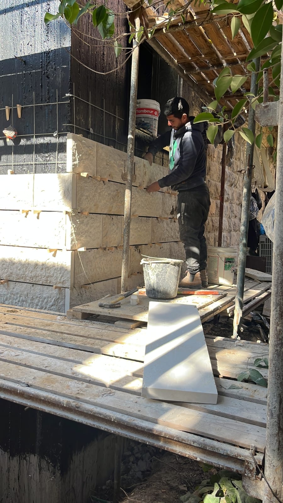 בעל מקצוע מתקין חיפוי אבן ירושלמית על המעטפת החיצונית